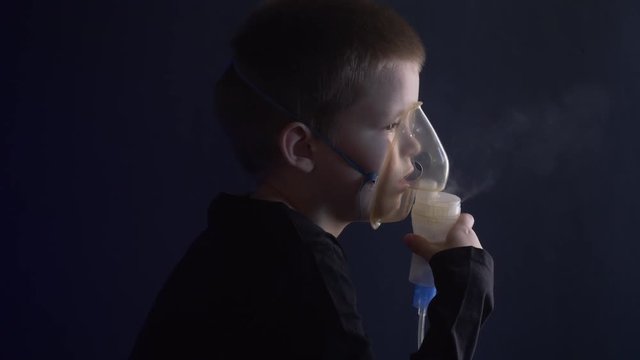 Caucasian blonde boy inhales couples containing medication to stop coughing. Medical procedures. Inhaler. Respiratory medicine. Bronchitis, asthmatic health equipment. Concept of home treatment.