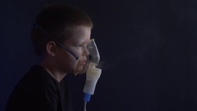 Caucasian blonde boy inhales couples containing medication to stop coughing. Medical procedures. Inhaler. Respiratory medicine. Bronchitis, asthmatic health equipment. Concept of home treatment.