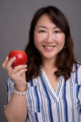 Mature beautiful Asian businesswoman holding healthy apple