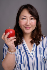Mature beautiful Asian businesswoman holding healthy apple