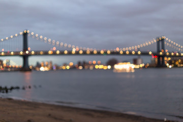 Blurred view on Manhattan bridge from the sand beach at sunset