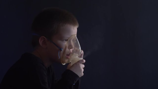 Caucasian blonde boy inhales couples containing medication to stop coughing. Medical procedures. Inhaler. Respiratory medicine. Bronchitis, asthmatic health equipment. Concept of home treatment.