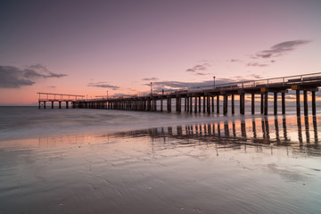 Fototapeta premium View on the pier from the sand beach at sunset, long exposure