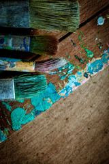 Dirty artist oil paint brushes in stacks on wooden background - portrait orientation  