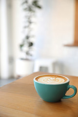 Hot cappuccino coffee in coffee shop on wooden table