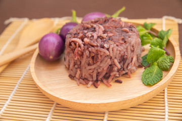 Clean food for healthy,cooked purple rice berry with peppermint leaves and purple eggplant on wooden plate