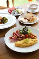 Breakfast set Omelette with sausage bacon and salad on wood background