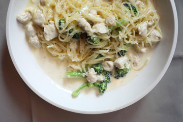 alfredo spaghetti broccoli chicken white sauce in restaurant background