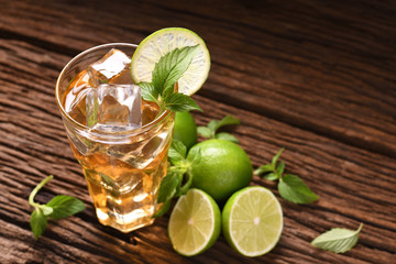 Iced lime honey tea in glass with mint and slice lime on wooden table