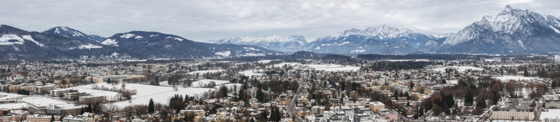 panoramic winter view of the historic center of Salzburg Austria surrounded by the Alps covered with snow in a foggy haze