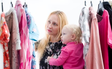 Woman with baby  chooses clothes in the wardrobe closet at home