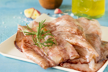 Fresh Squid close-up, Various Spices and Olive Oil on blue concrete or stone table.