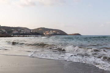 sea waves are broken by splashes and white foam on huge rocks in the warm Mediterranean sea in which boats and yachts