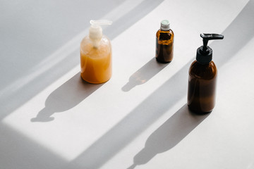 Clear plastic and glass brown bottles with organic cosmetics from above. Direct light. Beauty blogging minimalism concept