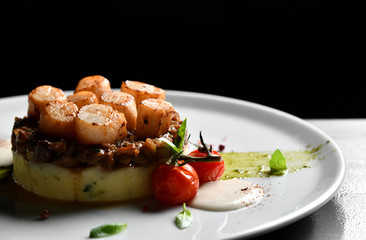 Plate with grilled scallops with butter lemon spicy sauce mashed potatoes and tomatoes