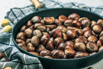 Roasted chestnuts served in chestnut pan on an old table