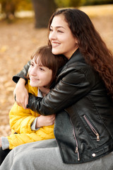 Two girls are in autumn city park.