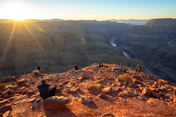 People sitting in various ways looking at Grand Canyon