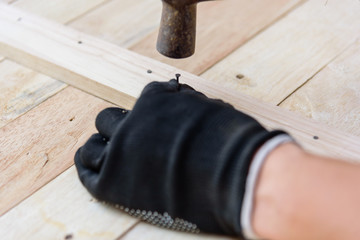 Worker hammer the nail into the wood