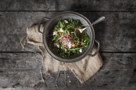Overhead view of rocket salad with goat's cheese and mealworms in wok