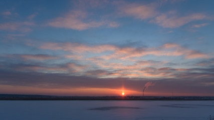 Cloudy winter sunset over the icy river in blue and orange, selective focus