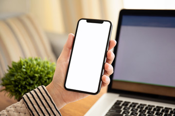 female hands holding touch phone with isolated screen in office