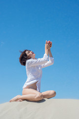 Woman is sitting on the sand and holding a red apple