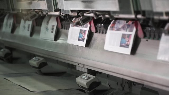 A big amount of ready-made newspapers on a printing house conveyor.