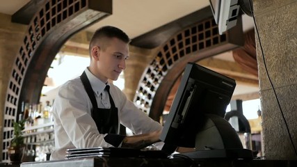 Man or waiter in apron at counter with cashbox working at the restaurant - Powered by Adobe