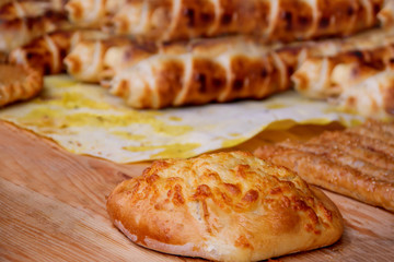 Khachapuri cheese puff on a wooden board in the background of sausage baked in a dough