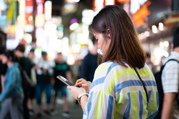 A woman is shopping online at the night street.