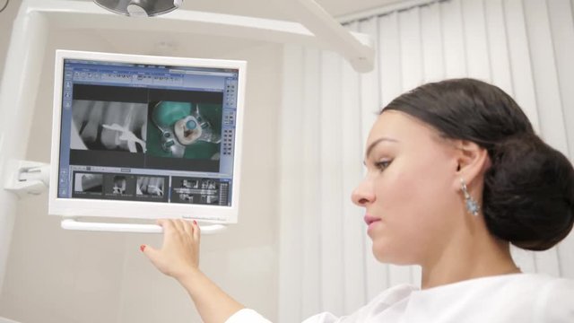 The dentist shows a picture of the x-ray on the monitor to the patient Young African American male patient at chair at dental clinic. Medicine, health, stomatology concept.
