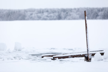 Grafting spade stick into ice. Making ice-hole for winter swimming in cold water