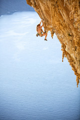 Young female rock climber on challenging route on cliff