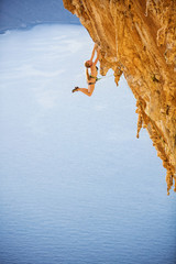 Female rock climber jumping on handholds on challenging route on cliff