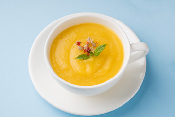 Pumpkin soup mashed with spices in a Cup on a blue background.