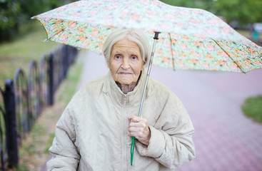 Senior woman under umbrella outdoors