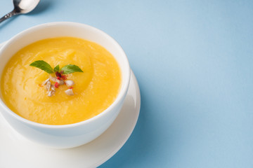 Pumpkin soup mashed with spices in a Cup on a blue background.