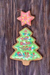 Colorful Christmas gingerbread in the shape of a Christmas tree and in the shape of a star decorated with green and red icing on a wooden board