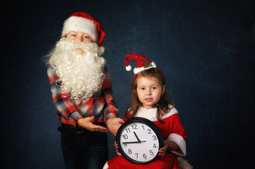 funny brother and sister in Christmas costumes on dark background . Children waiting for Christmas