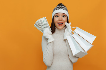 Money. Shopping. Woman portrait. Accessories. Asian girl in a white polo neck, cap and gloves is...