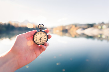 Vintage watch hand-held, autumwn view with lake and trees in the background