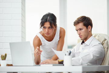 Caucasion man and woman working together in a modern office