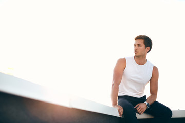 Young man in sportswear sitting on a rooftop