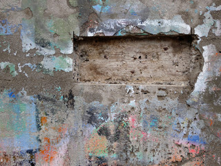 damaged wall with all kind of colors on it and a rectangled hole