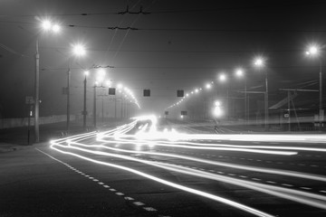 Cars drive at speed through the city at night.