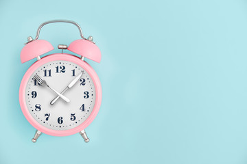 Alarm clock. Fork and knife instead of clock hands. Concept of intermittent fasting, lunchtime, diet and weight loss