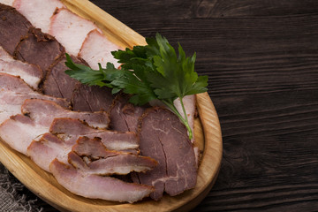 Delicious smoked pork fillet, veal fillet and pork brisket on wooden board. Cold meat  snack. Copyspace