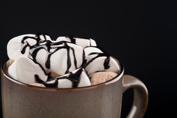 Coffee with marshmallow. Tasty hot drink with sweet marshmallow on a black