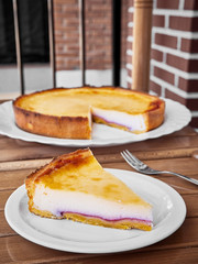 A slice of Homemade Cheese cake over a wooden table.